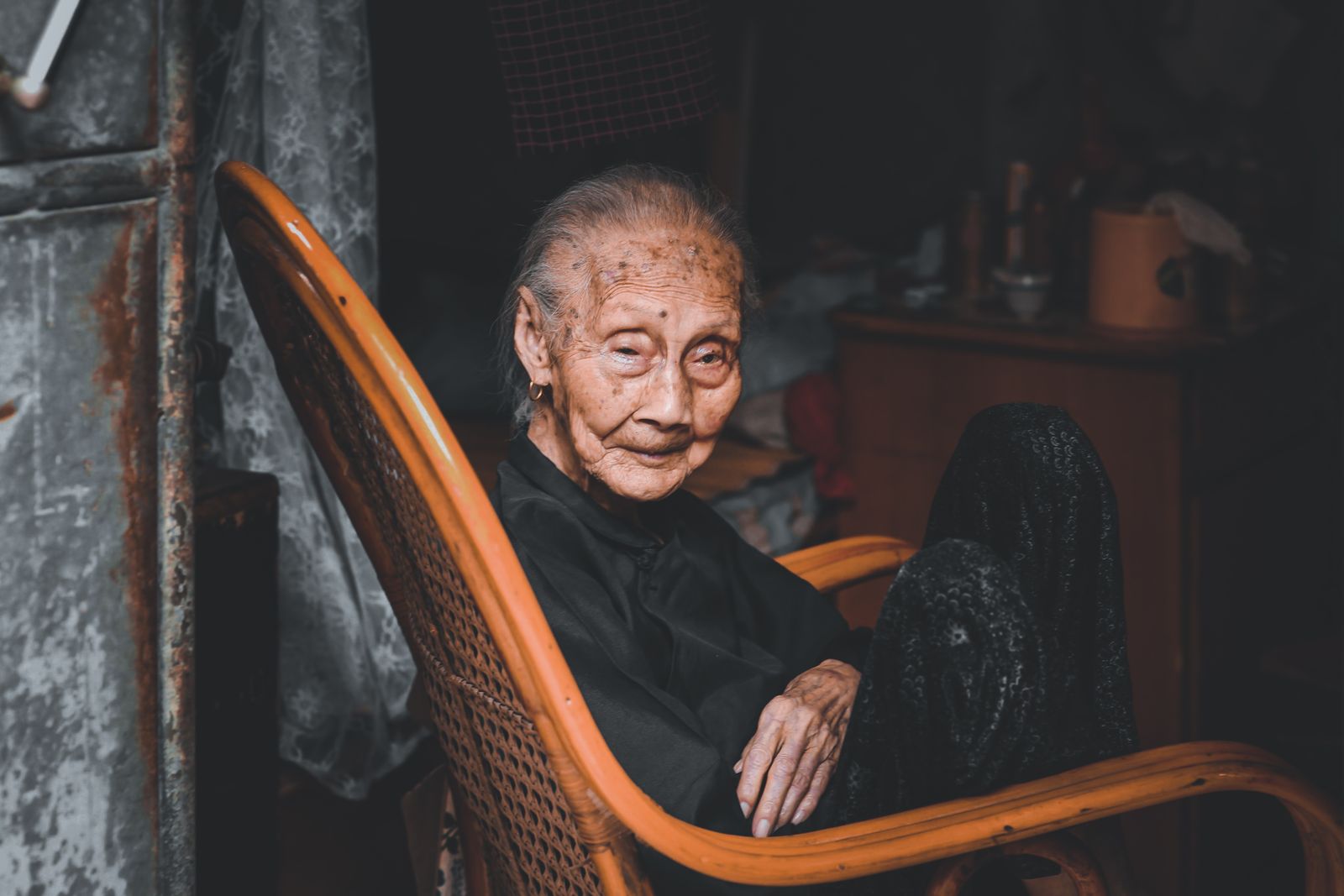 An older woman sitting comfortably in an armchair in her own home.