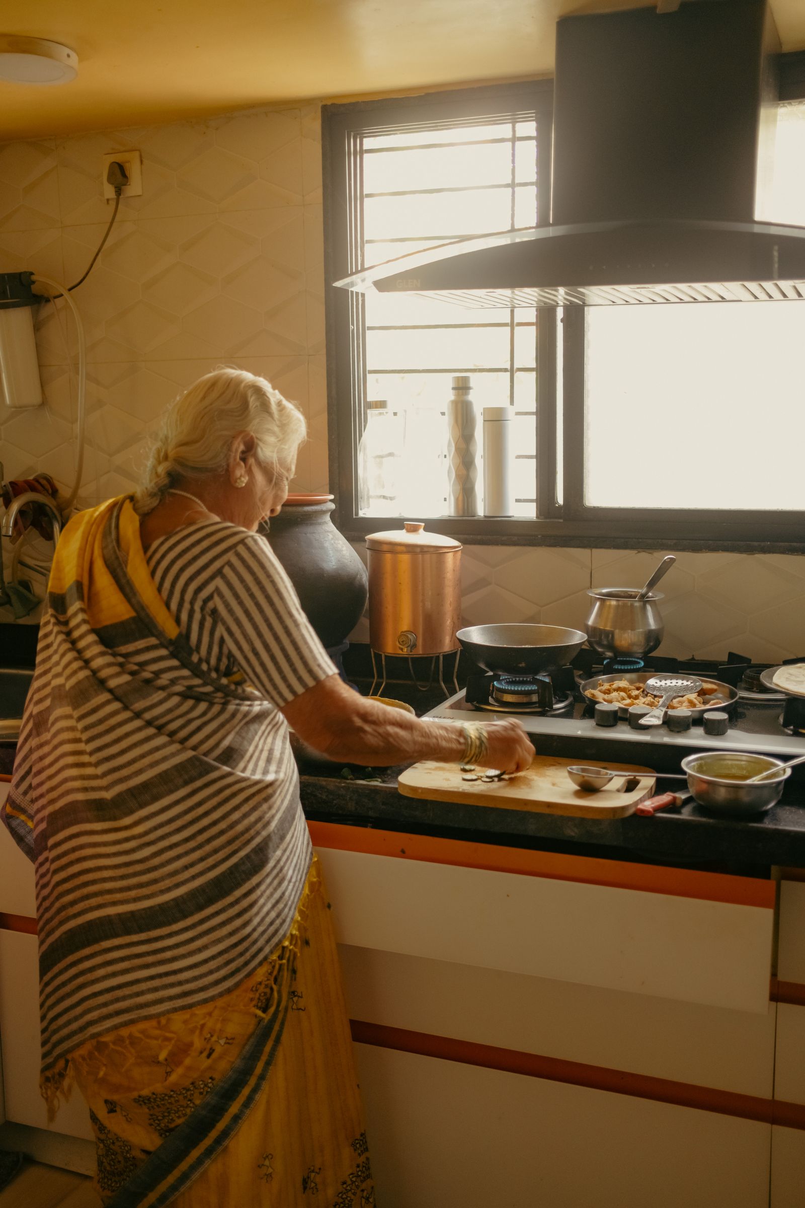 An older woman preparing food in her own kitchen.