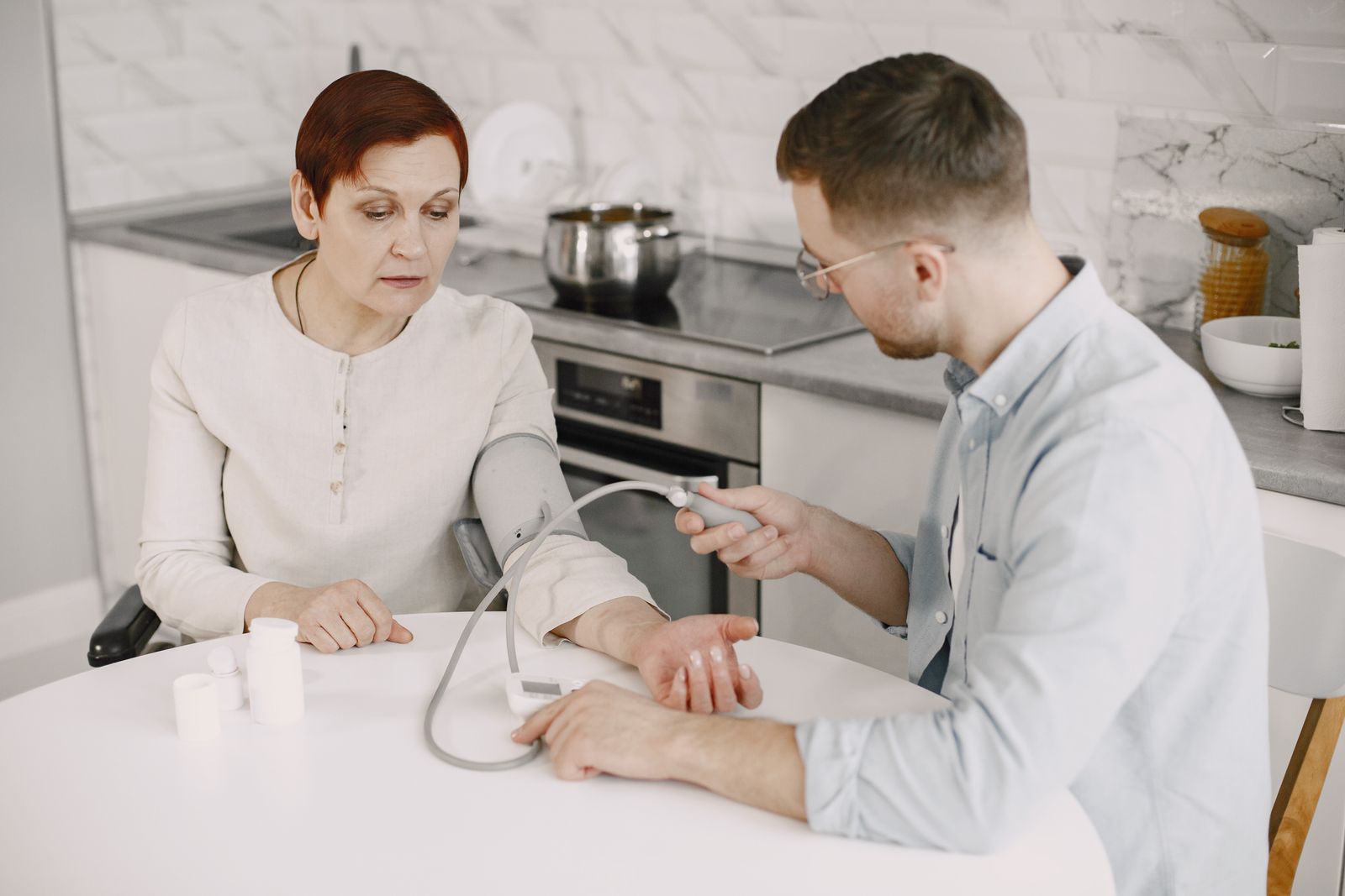 Two care workers helping an older person at a table at home.