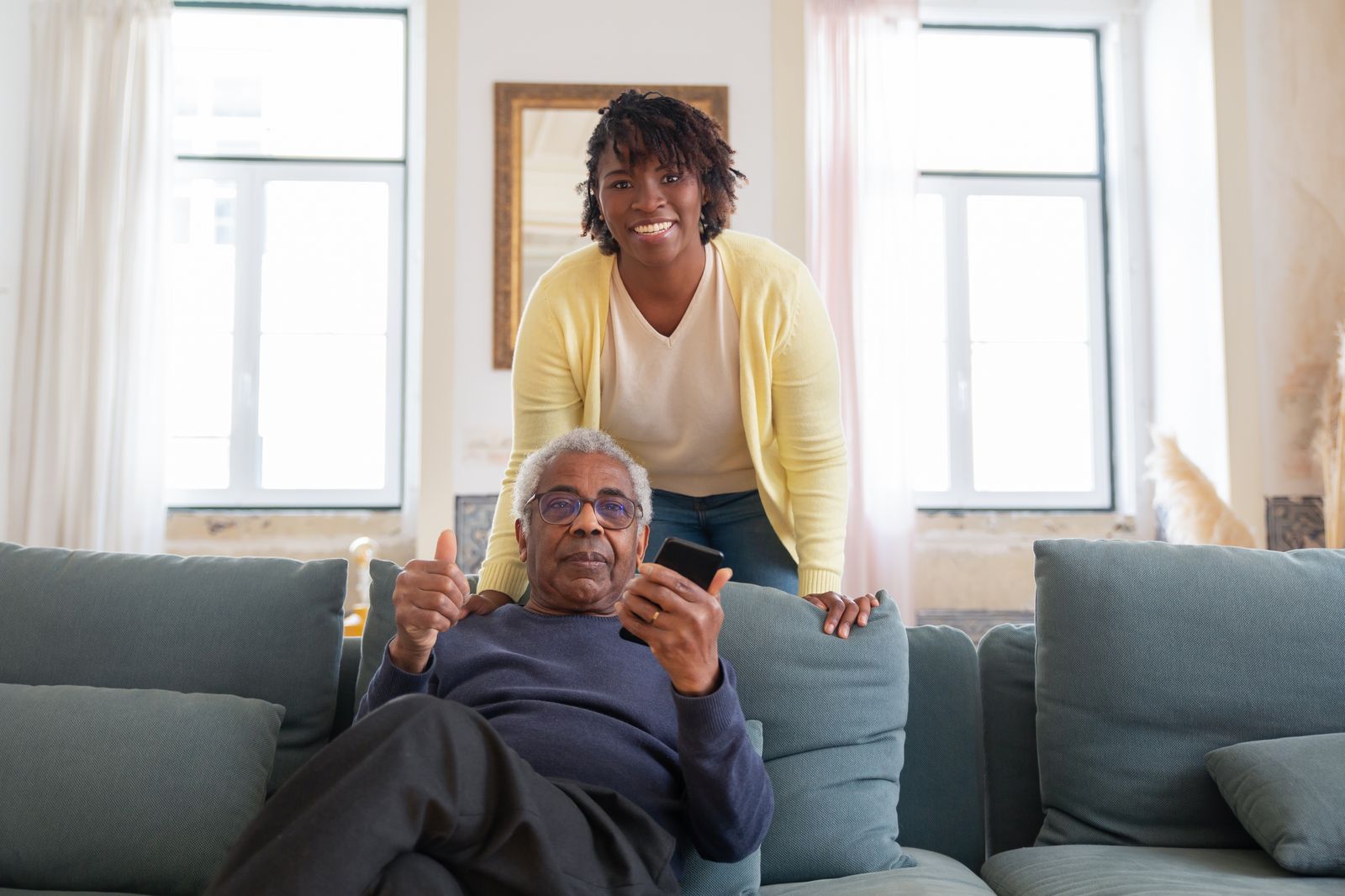 A carer and an older man sharing a laugh in the living room.
