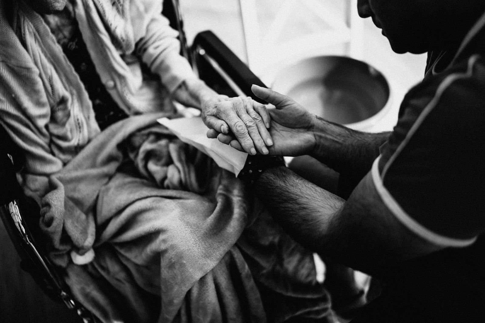 A carer gently holding the hand of an older person.