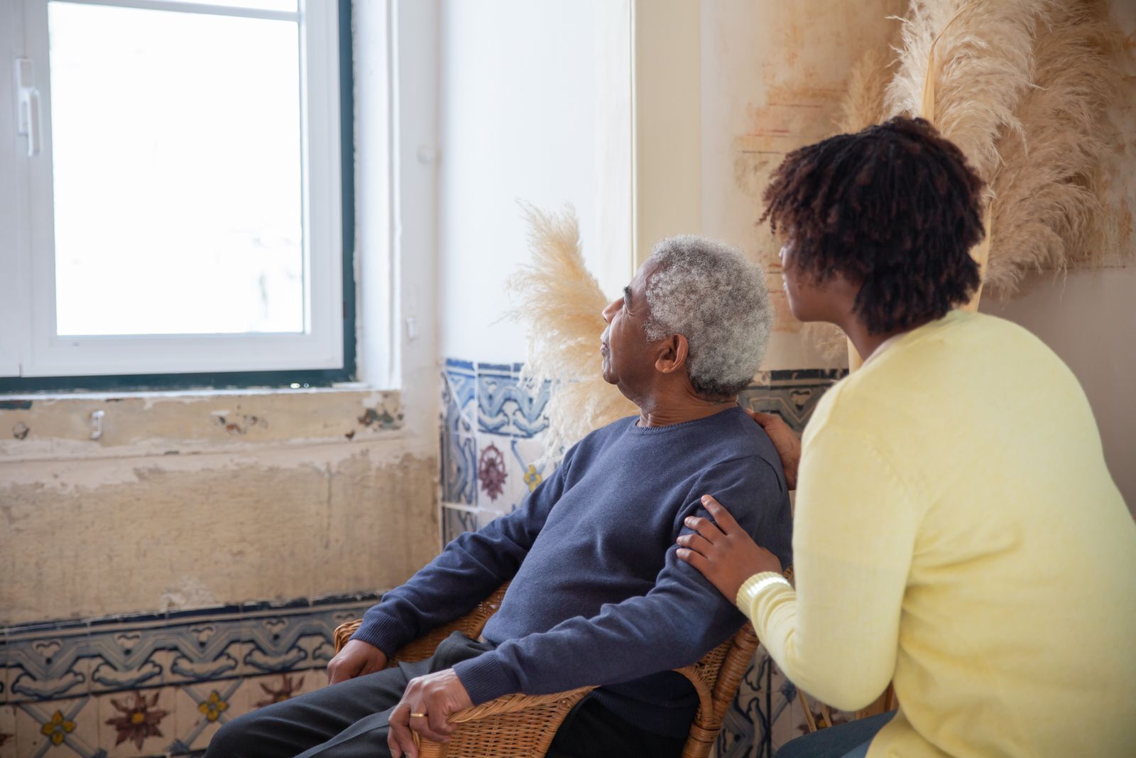 A carer and an older man talking together at home.